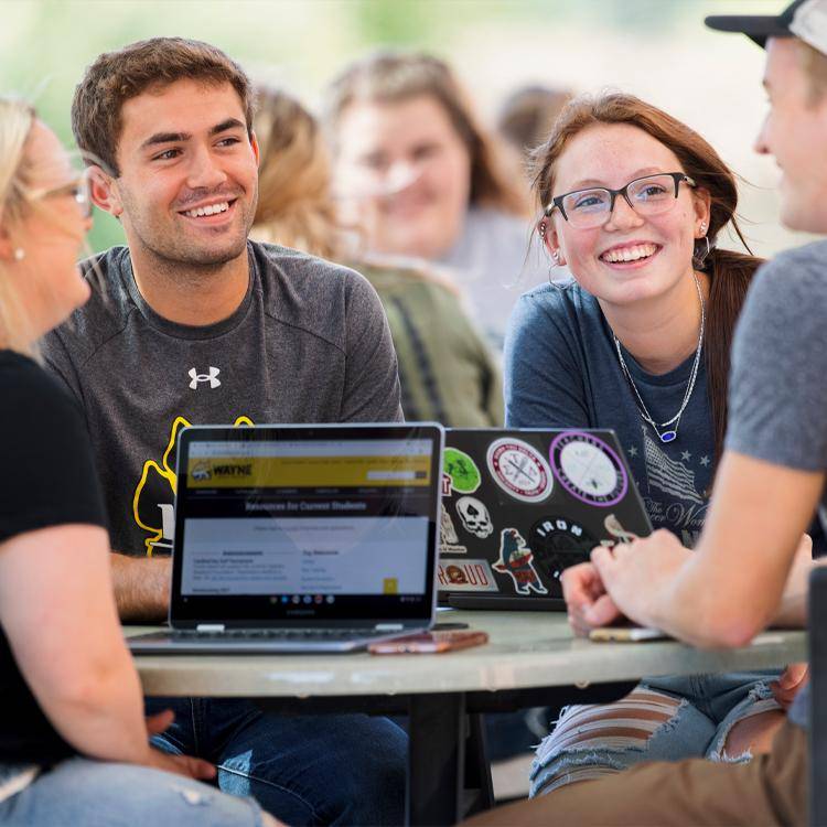 Students gather at a table outside the library