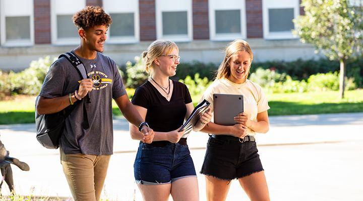 Three students walk on campus