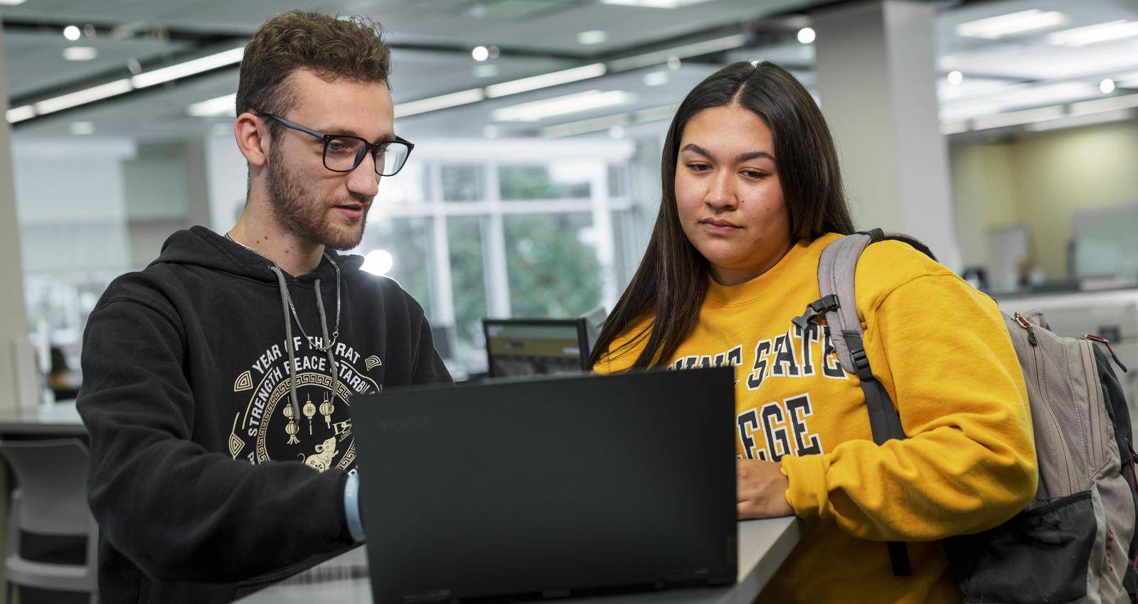 A student working at the Service Center helps another WSC student