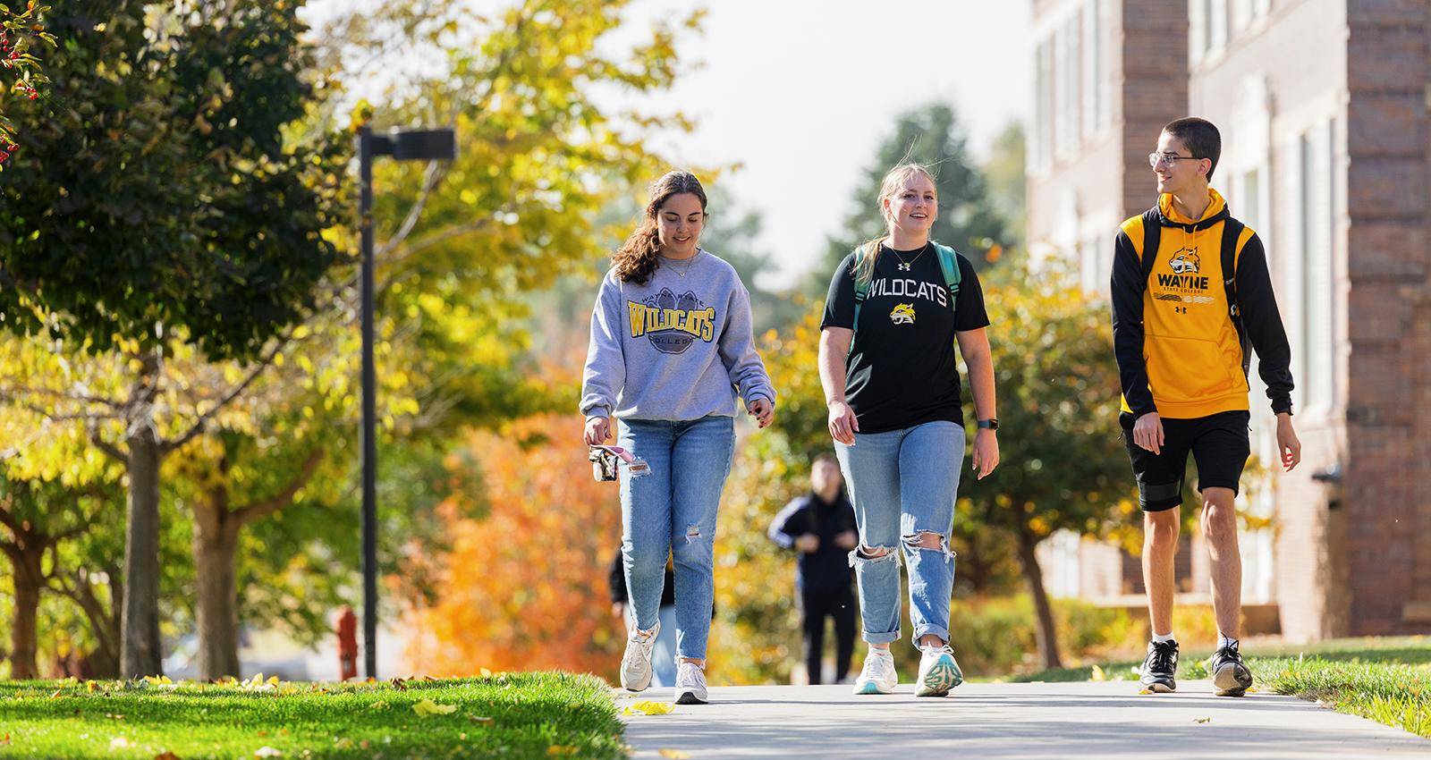 Three students walk outdoors on campus